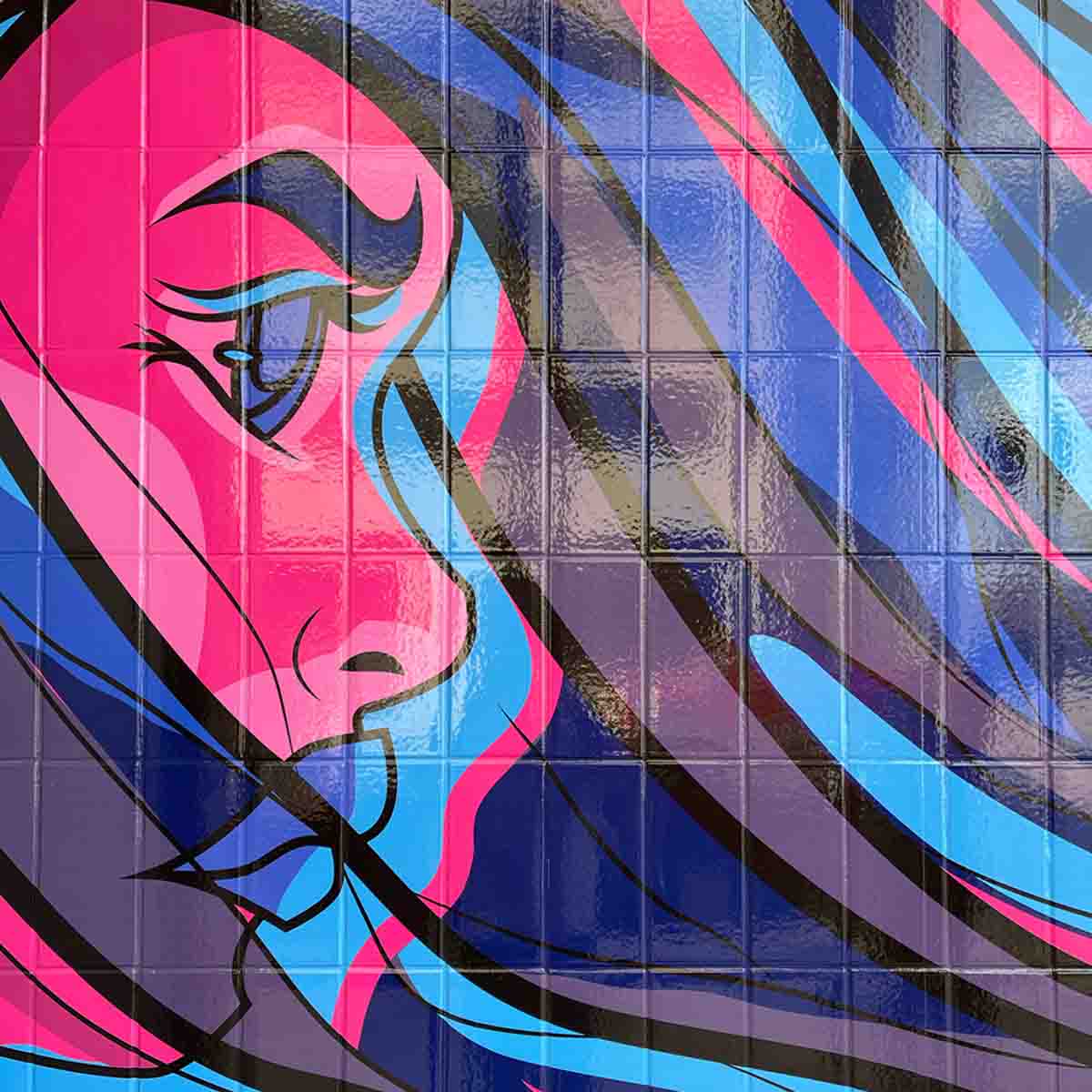 Street mural on a brick wall depicting a woman's face in profile with long, flowing hair in shades of pink and blue.