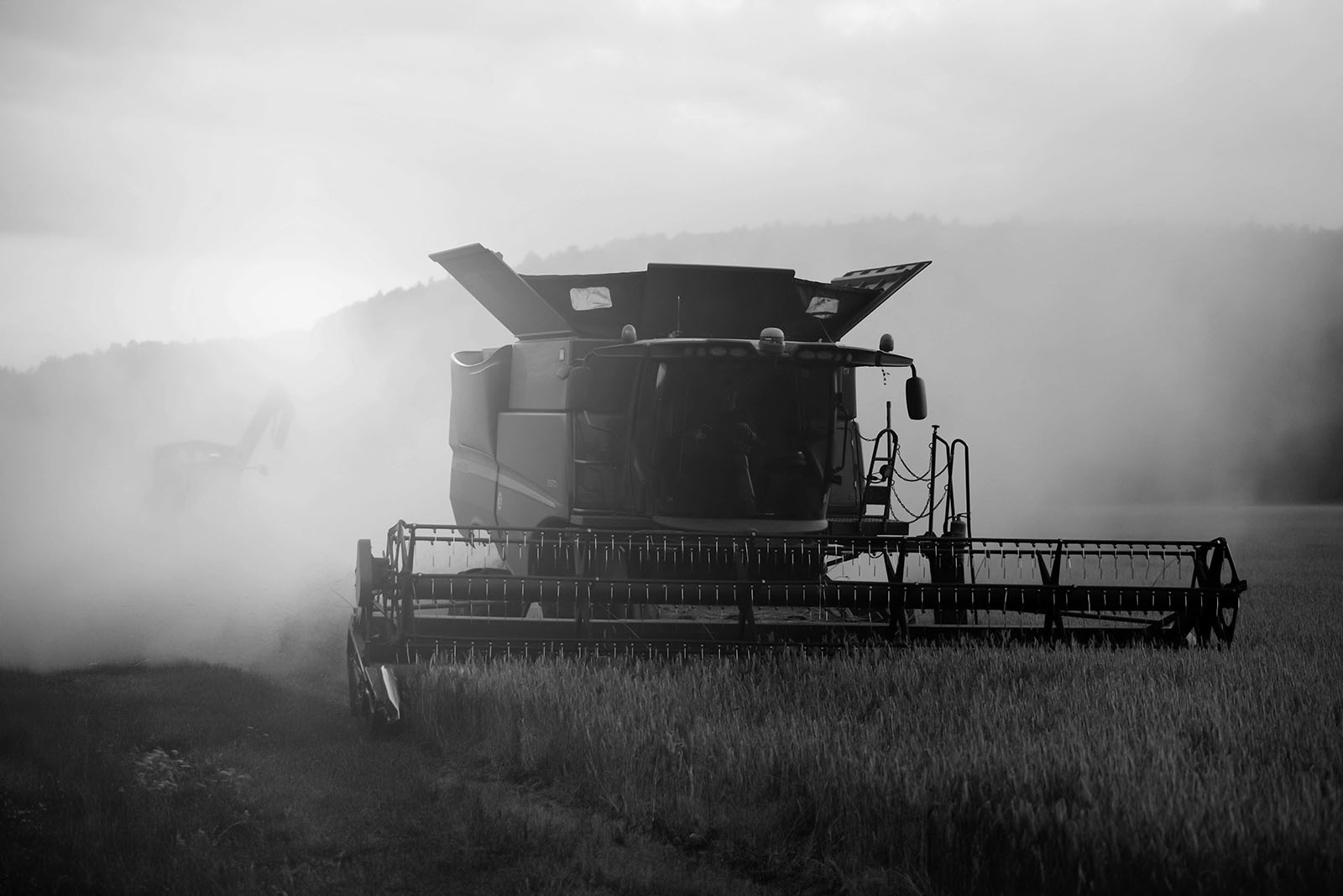 Black and white photograph of a combine harvester in the middle of a field